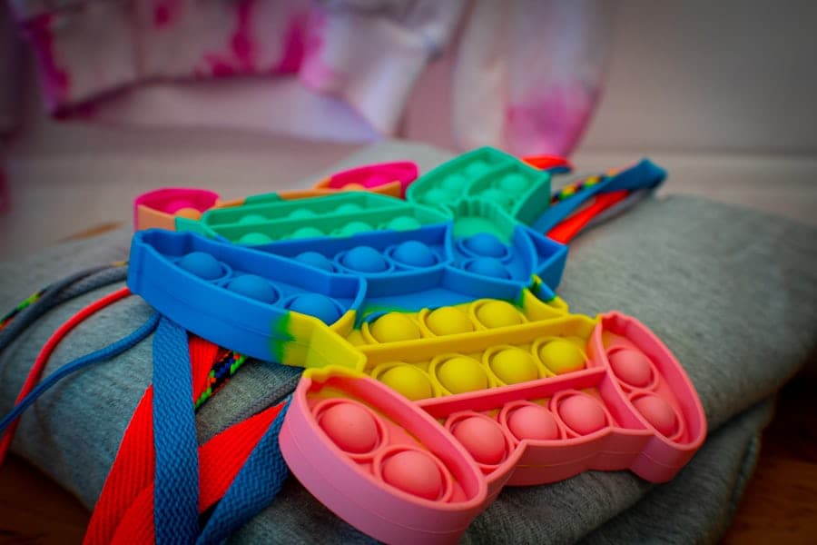 Colorful stacked silicone pop-it fidget toys resting on a soft grey sweater.